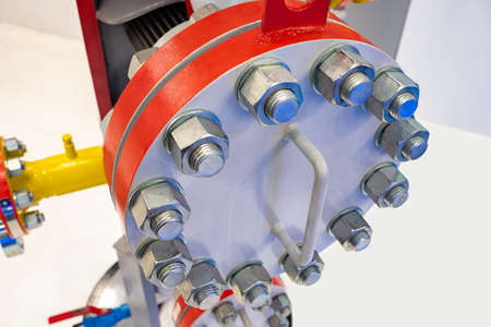 Pipeline section close up. Bolts and nuts of pipeline. The pipe system in the enterprise. Transitional cast iron flange. Transportation of oil through pipes. Pipeline with big flanges.の写真素材