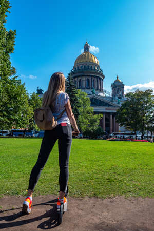 Russia. Saint Petersburg. Saint Isaac's Cathedral. The girl on the scooter. Girl on a scooter in Petersburg. A student looks at St. Isaac's Cathedral. Tours in St. Petersburg. Traveling in Russia.の写真素材