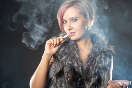 Tobacco heating system. Electronic Cigarette. Girl with a tobacco heating system. Woman with a device for heating tobacco. An alternative to cigarettes. Gadget for smoking. E-cig.の写真素材