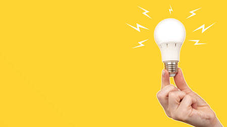 LED light bulb on orange background. Frosted white light bulb in hand. Concept - sale of LED lamps....