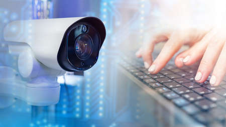 CCTV camera next to keyboard. Camera monitoring concept. Setting up CCTV systems. CCTV camera control. Administration of video surveillance systems. Tracking by using CCTV. Partial blurredの写真素材