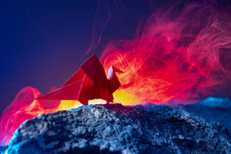Dragon made of paper. Red Paper Draco Origami. Draco stands in the light of the lava. Metaphor of a red Chinese dragon. Conceptual image - revival of China. Fake paper on the background of the volcanoの写真素材