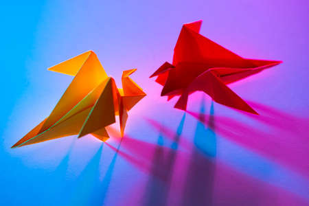 Metaphor is an equal battle. Concept - a conflict of interest. Fight for customers in business. Competitors in business. Look into the eyes of your fears. Origami from colored paper. Miniature dragonsの写真素材