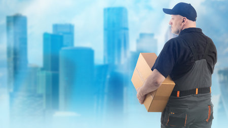 Courier with parcel. Delivery man has his back to camera. Male courier on blurred blue background....