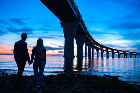 Man and woman. Love. Guy and the girl look into the distance. Lovers stand under the bridge. Newlyweds are looking at the bay. Lovers dream to leave. Dreams of a vacation. Walking by the pondの写真素材