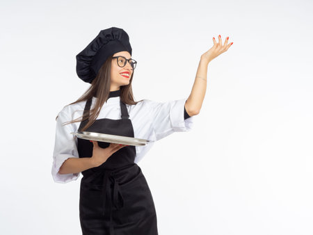 Chef with empty tray. Woman chef smiling. Empty food display tray. Girl cook waves her hand. Copy space for your restaurant. Chef cook in good mood. Restaurant business worker on light backgroundの写真素材