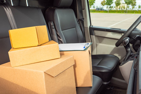 delivery box on car seats. Courier van inside view. Delivery box next to courier driver's seat. Courier logistics concept. Delivery company logistics. Boxes represent postal parcels.の写真素材
