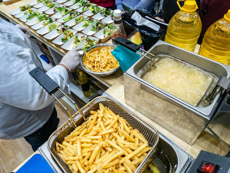 Buffet preparation. chef preparing food for takeout. Deep-fried and fried potatoes next to chef. Catering chef. cook puts food in disposable plates. Concept - street food. Disposable salad platesの写真素材