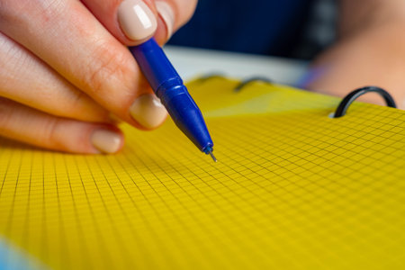 The pen next to notebook. yellow page of blank note next to pen. man writes something in notebook....