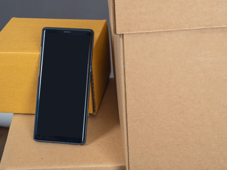 phone is next to cardboard boxes. Concept - Application for sending parcels. Screen off phone. Place...