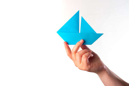 Paper ship in the hand. Blue boat. The concept is medium business. The concept is stability in business. Metaphor - free swimming. Company management. Point in the right direction. Correct Directionの写真素材