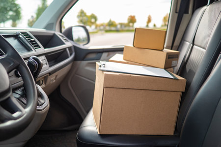 delivery box in minivan. Delivery box as symbol of courier logistics. Concept - delivery of goods from online stores. Courier logistics of online store. Cardboard boxes in driver's seat of vanの写真素材