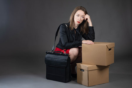Fired wom Tired girl with boxes. Corton boxes as symbol of dismissal. woman looking tired. Concept -...