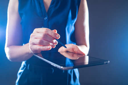 Tablet PC. Girl with gadget. Woman using digital tablet computer. Businesswoman on dark background. Woman in dress is partially blurred. Concept - She demonstrates application. Using business appsの写真素材