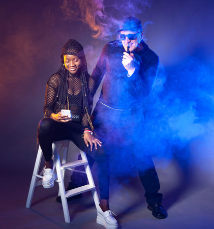 E-cigarette. Vapers take selfies. Selfie in a cloud of steam. A guy and a girl smoke and take...