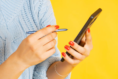 Woman using smartphone and stylus. Close up of lady using her cell phone. Female hands with an...