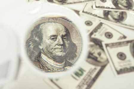 View money under a magnifying glass. Magnifier over a hundred dolaravye notes. Checking the finances of the enterprise. Analysis of the financial report. Tax audit in business. Invoice Verificationの写真素材