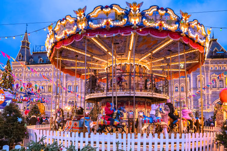 Moscow. Russia. Children's attractions on the Red Square. Christmas market in the evening. Children on the carousel next to the Kremlin. Entertainment for tourists in the center of Moscow. 10.01.2020のeditorial素材