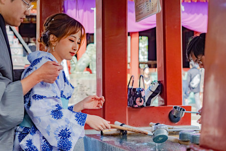 Tokyo. Japan. Japanese woman in a kimono. Young girls wash their hands in front of the temple. Culture Japan. Tourists clean their hands before visiting the temple. Holidays in Tokyo. 09/11/2019のeditorial素材