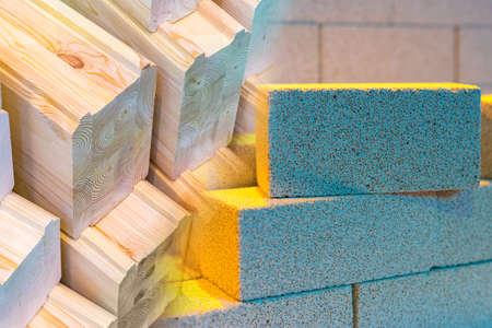 construction materials. Wooden beams next to the brick. foam block. Comparison of wood and brick. Comparison of building materials. Concept - sale of materials for building a house.の写真素材
