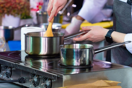 Cooking Cook cooks in the restaurant kitchen. Cook on the stove heats the dish. Stewpan. A man...