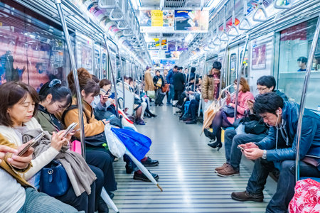 Japan. People ride the Tokyo subway. All people in the subway use the phone. Residents of Japan returning from work. People use the phone while riding the subway. Tokyo residents. 11.23.2019のeditorial素材