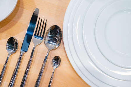 Table setting in a restaurant. fancy cutlery. Cutlery serving option. plates. Concept - Sale of individual tableware. guest services. Concept - restaurant business. Utensils on a wooden table.の写真素材