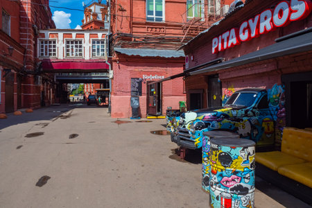Moscow. Russia. The streets of Moscow. Walking along the streets of the capital. Part of the car sticks out of the wall. Exterior of the cafe. Car and barrels are decorated with graffiti. 07.20.2019のeditorial素材