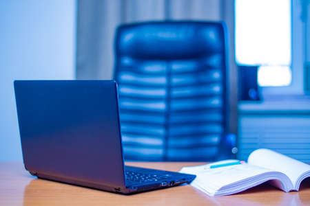 Director's workplace. A laptop next to a large pile of documents. Laptop on the director's desk. empty office. Interior office for the head. Sale of furniture for offices. Concept - lack of a leaderの写真素材