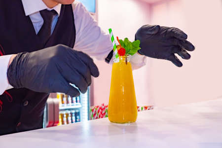 Bartender is cooking a cocktail. Restaurant employee prepared freshly squeezed juice. Barista. Concept - work as a bartender. Bartender made a soft drink. Man serving a drink. cold drinksの写真素材