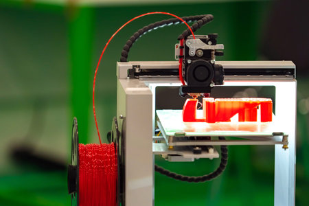 3D printer during operation. The 3D printer prints with a red cartridge. 3D printer close-up....