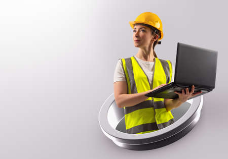 engineer woman. Girl builder with laptop. Woman in yellow vest and helmet. Woman architect on grey. Place for text on topic of construction. Employee of construction company. Work as engineerの写真素材