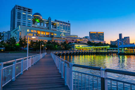 Japan. Odaiba Island Embankment. Unusual building in Tokyo. Modern architecture of Japan. Dawn on the island of Odaiba. Embankment of morning Tokyo. Wooden marina leads to the city promenadeの写真素材