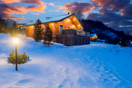Country house in snow drifts. Winter cottage. Wooden house in winter evening. Cottage at foot of...
