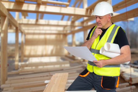 man constructor. home construction. representative architectural bureau. Thoughtful construction worker scratching his chin. Man in vest and construction helmet. Constructor in unfinished houseの写真素材