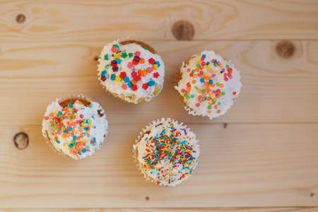 Easter cupcakes with cream and small confetti on a wooden table. Spring.の写真素材