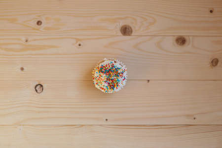 Easter cupcakes with cream and small confetti on a wooden table. Spring.の写真素材