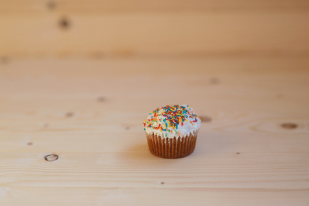 Easter cupcakes with cream and small confetti on a wooden table. Spring.の写真素材