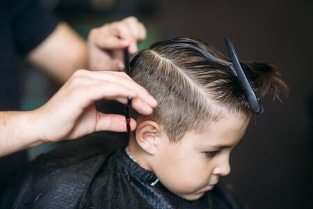 Little Boy Getting Haircut By Barber While Sitting In Chair At Barbershop.の写真素材