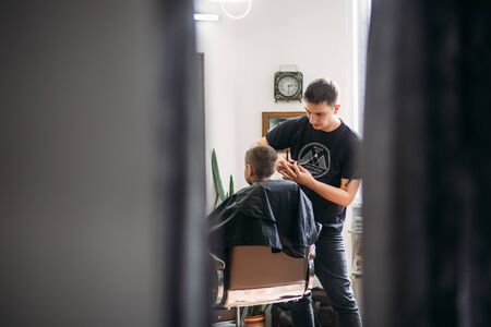Little Boy Getting Haircut By Barber While Sitting In Chair At Barbershop.の写真素材