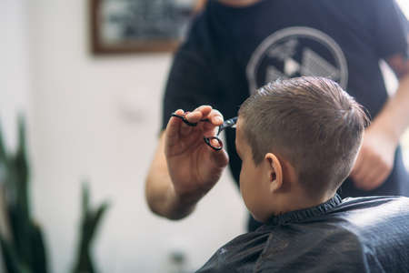 Little Boy Getting Haircut By Barber While Sitting In Chair At Barbershop.の写真素材