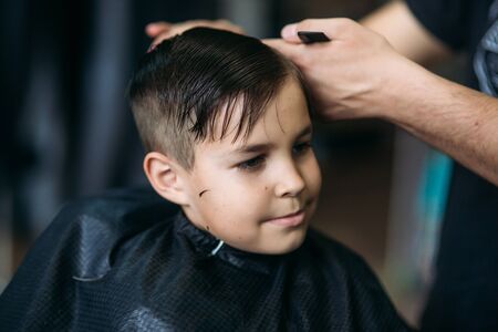 Little Boy Getting Haircut By Barber While Sitting In Chair At Barbershop.の写真素材