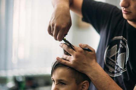 Little Boy Getting Haircut By Barber While Sitting In Chair At Barbershop.の写真素材