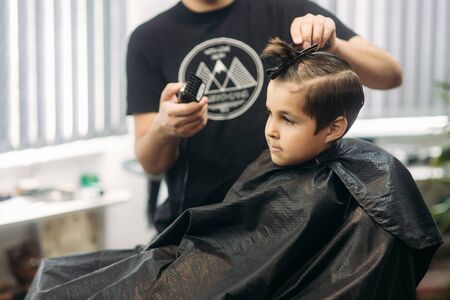 Little Boy Getting Haircut By Barber While Sitting In Chair At Barbershop.の写真素材