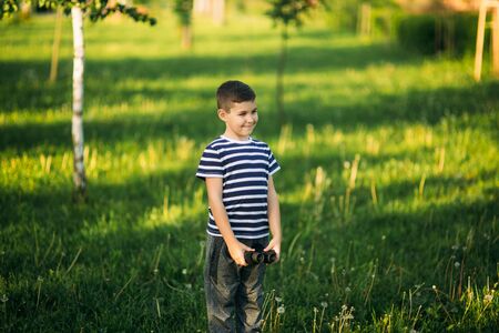Little boy in a striped t-shirt looks through binoculars .Spring, sunny weather.の写真素材