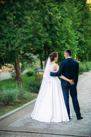 Young couple, bride and groom walking and enjoying their wedding day. Sunshine. Summer.の写真素材
