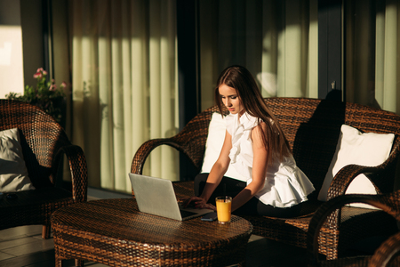 Young beautiful girl use a laptop during a break at work. Summer sunny day.の写真素材