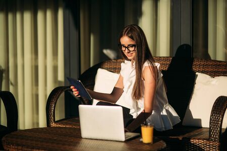 Young beautiful girl use a laptop during a break at work. Summer sunny day.の写真素材