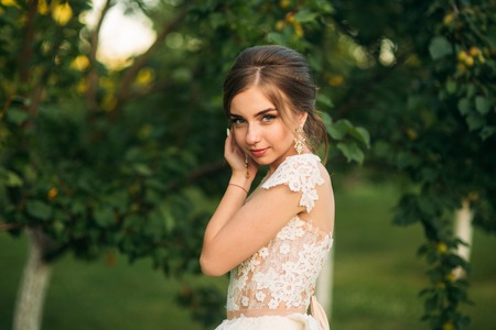 Young girl in wedding dress in park posing for photographer. Sunny weather, summer.の写真素材