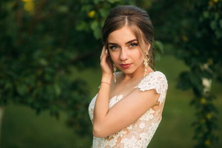 Young girl in wedding dress in park posing for photographer. Sunny weather, summer.の写真素材